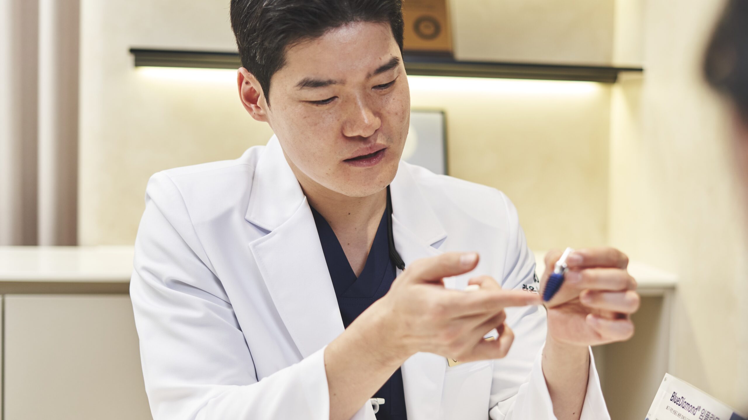 치과 전문의가 환자에게 임플란트 모형을 보여주며 잇몸뼈 상태와 치료 계획에 대해 설명하는 모습